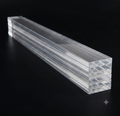 A stack of clear acrylic or polycarbonate rectangular strips shown diagonally on a solid black background.